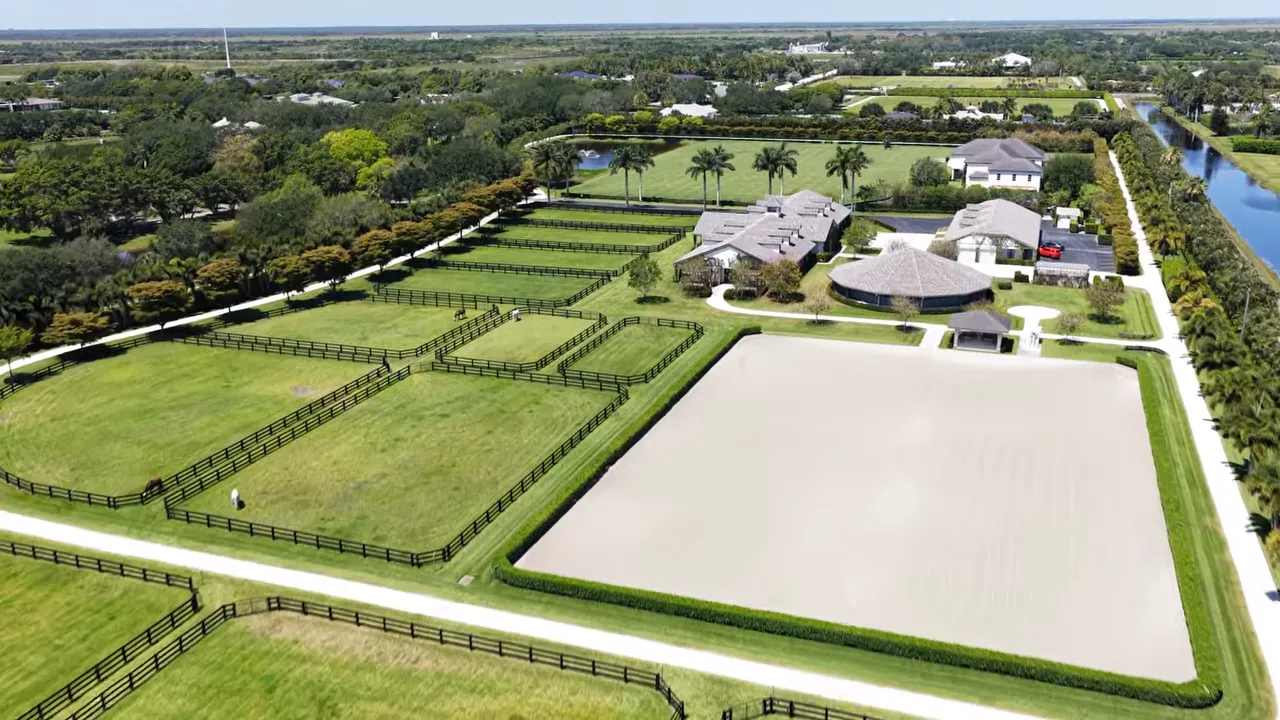 Aerial view of a horse property in Wellington, Florida with fenced paddocks and a large outdoor riding arena