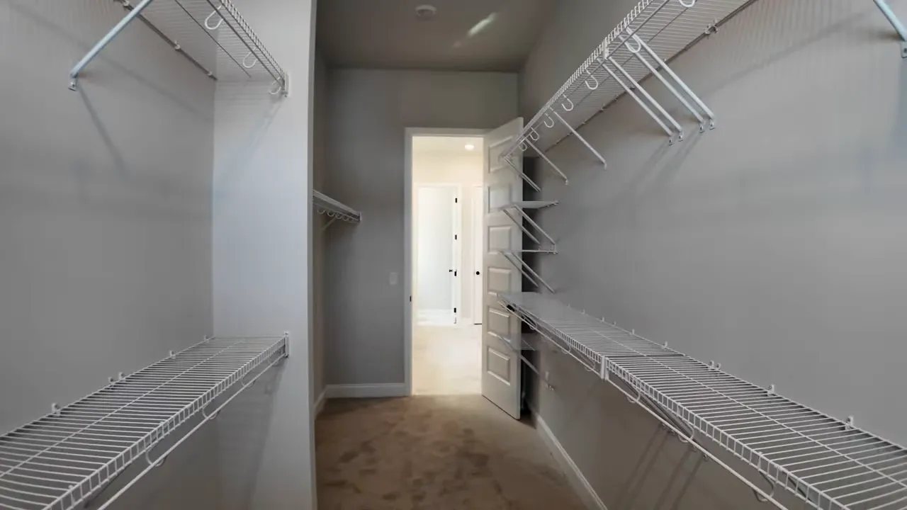 Large primary suite closet with built-in shelving and hanging rods in a Summers Corner SC new construction home
