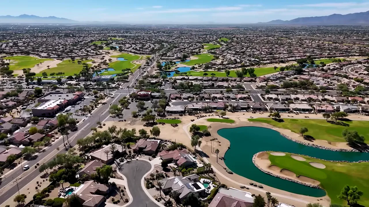 Aerial view of a Phoenix-area 55+ golf community with clubhouse, homes, and water features