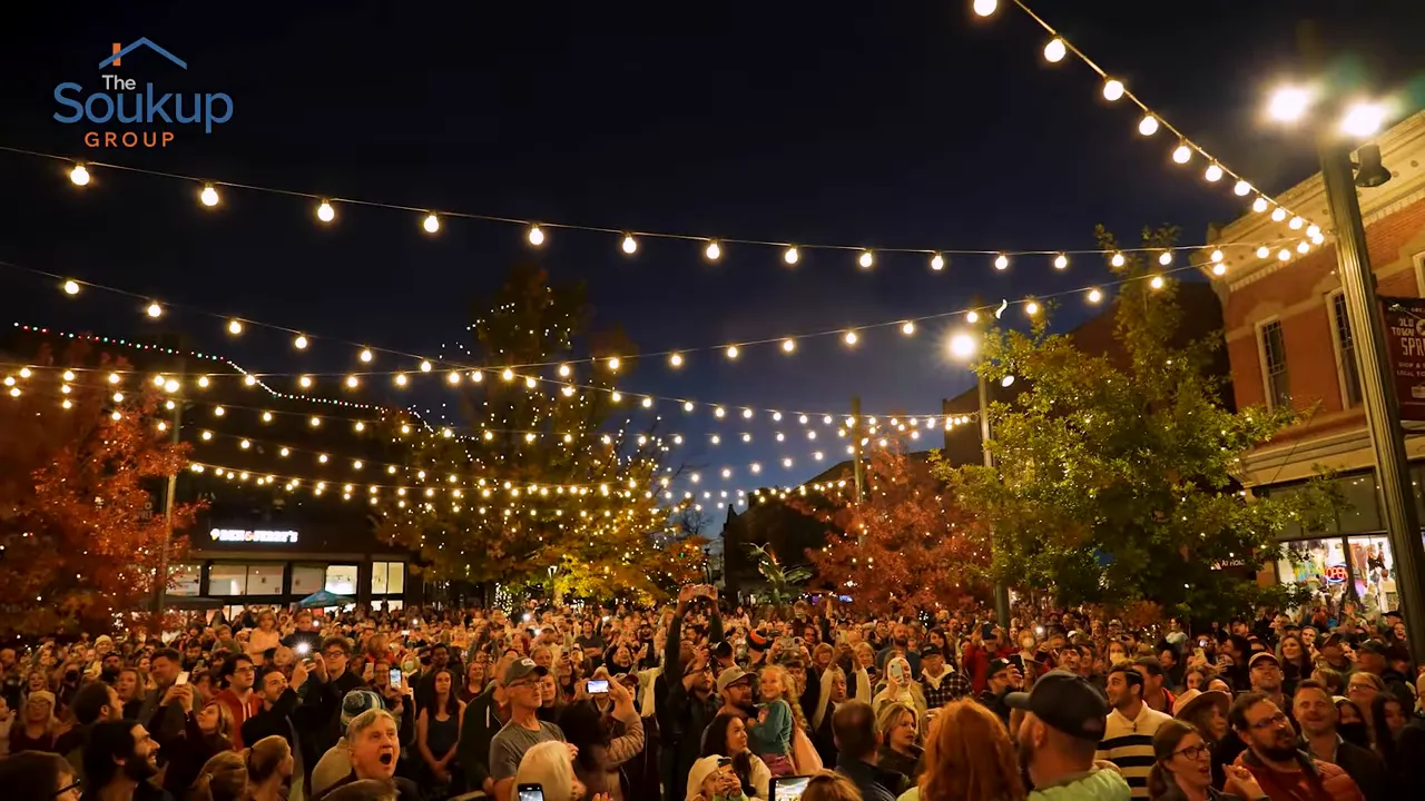 Large crowd gathered beneath string lights in Old Town Fort Collins