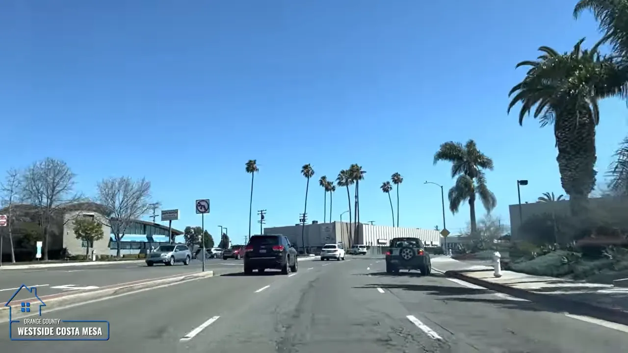 Road view driving through Westside Costa Mesa with palm trees under a clear blue sky
