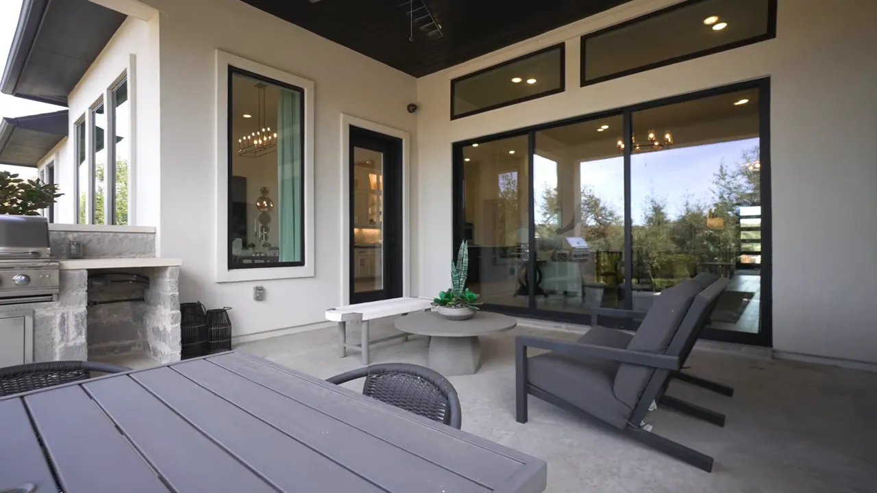 Covered outdoor patio with seating built-in grill and backyard beyond