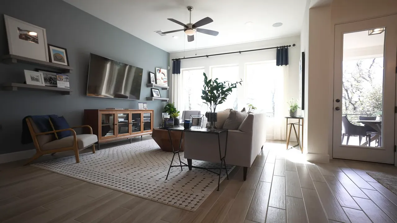 Living room with sofa chairs ceiling fan and large back windows