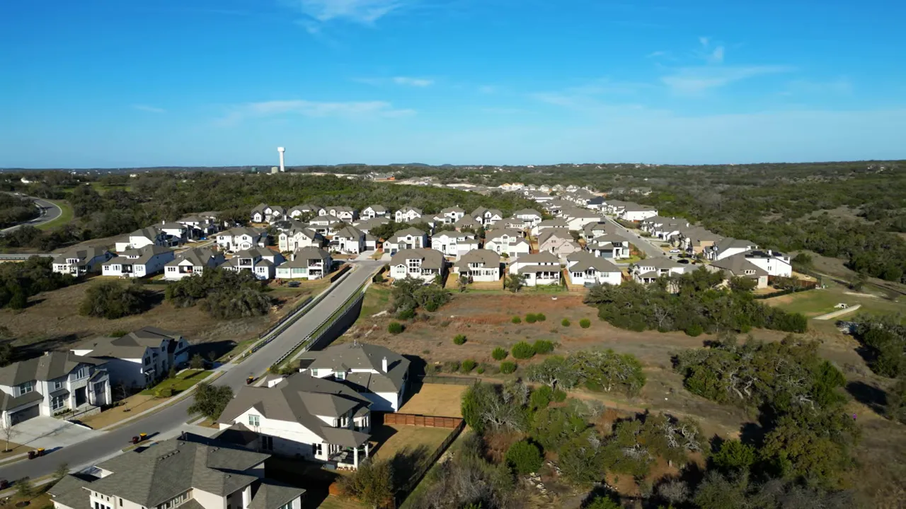 Aerial view of a large neighborhood surrounded by green Hill Country land