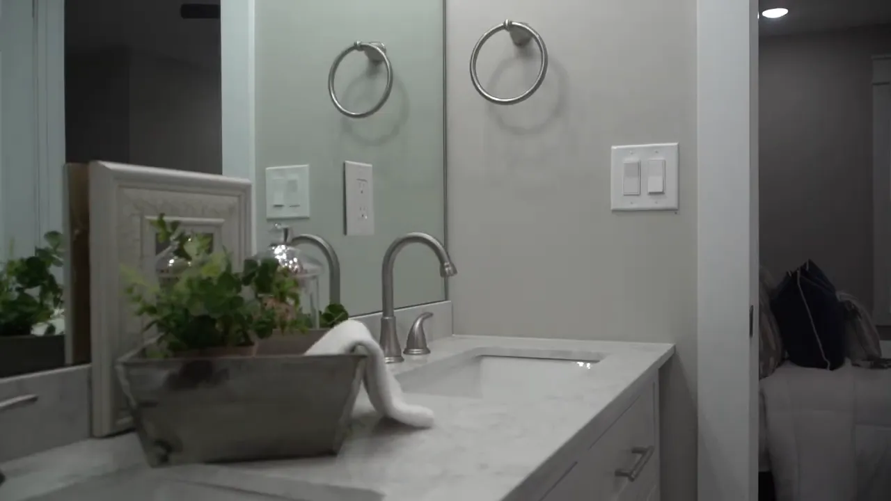 Primary bathroom double vanity with two sinks, mirror, and light marble-look countertop