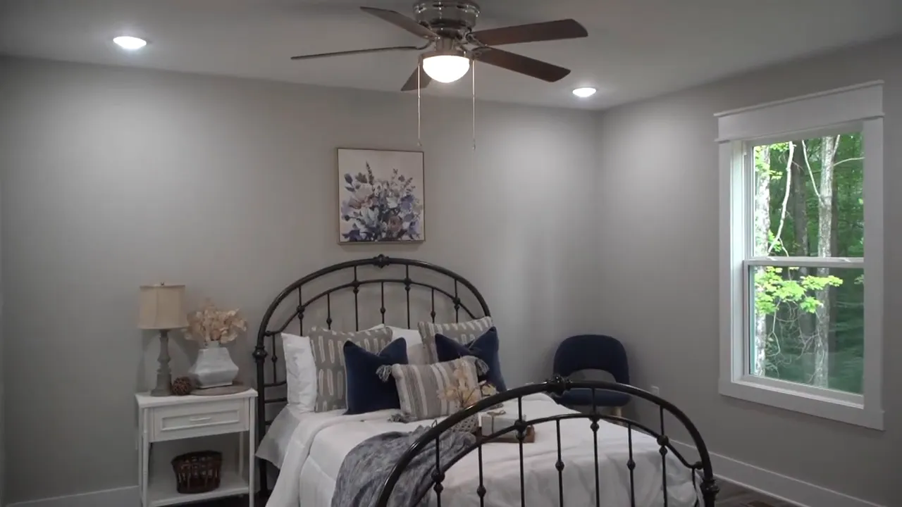Primary bedroom with bed, ceiling fan, recessed lights, and window facing trees