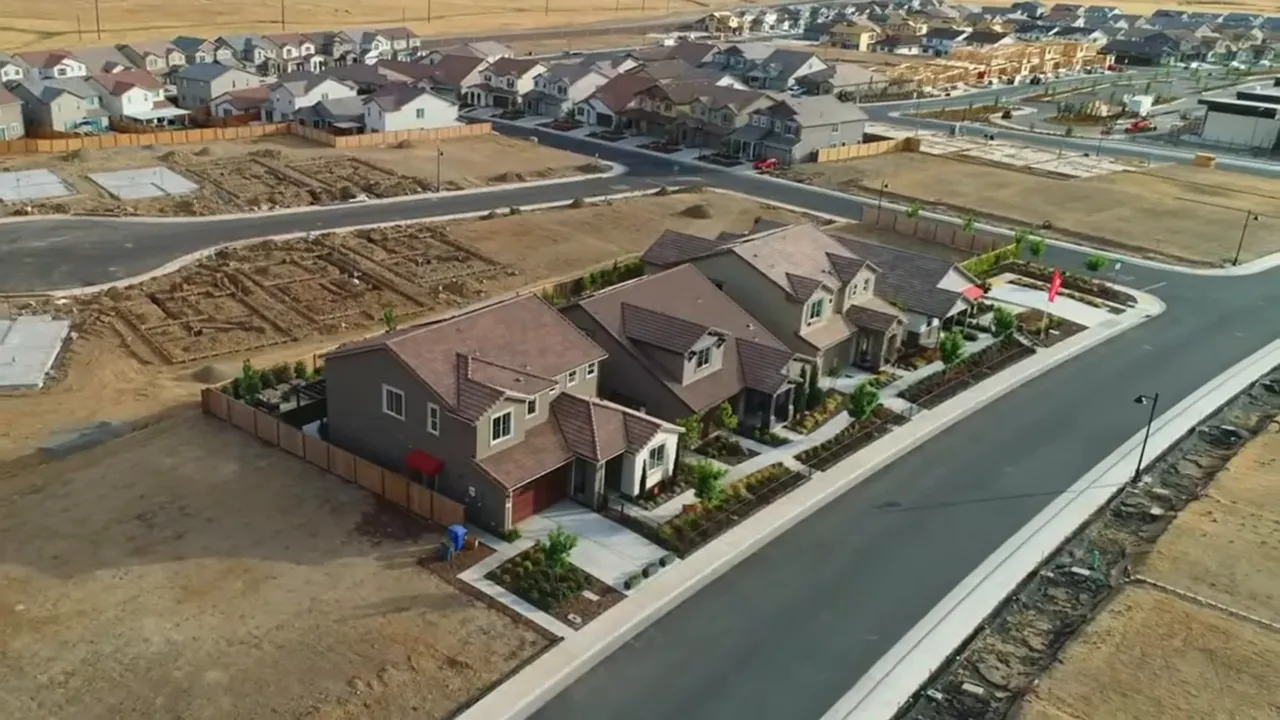 Drone shot of newly built single-family homes with adjacent construction pads in a master-planned neighborhood