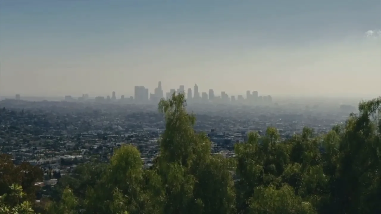 Hazy Phoenix skyline seen from a hillside above neighborhoods and trees