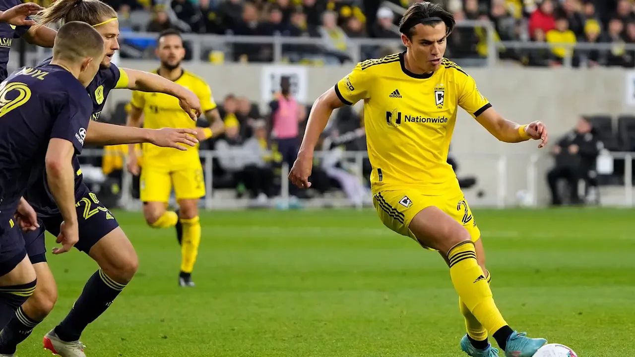Columbus Crew soccer player in yellow uniform kicking a ball