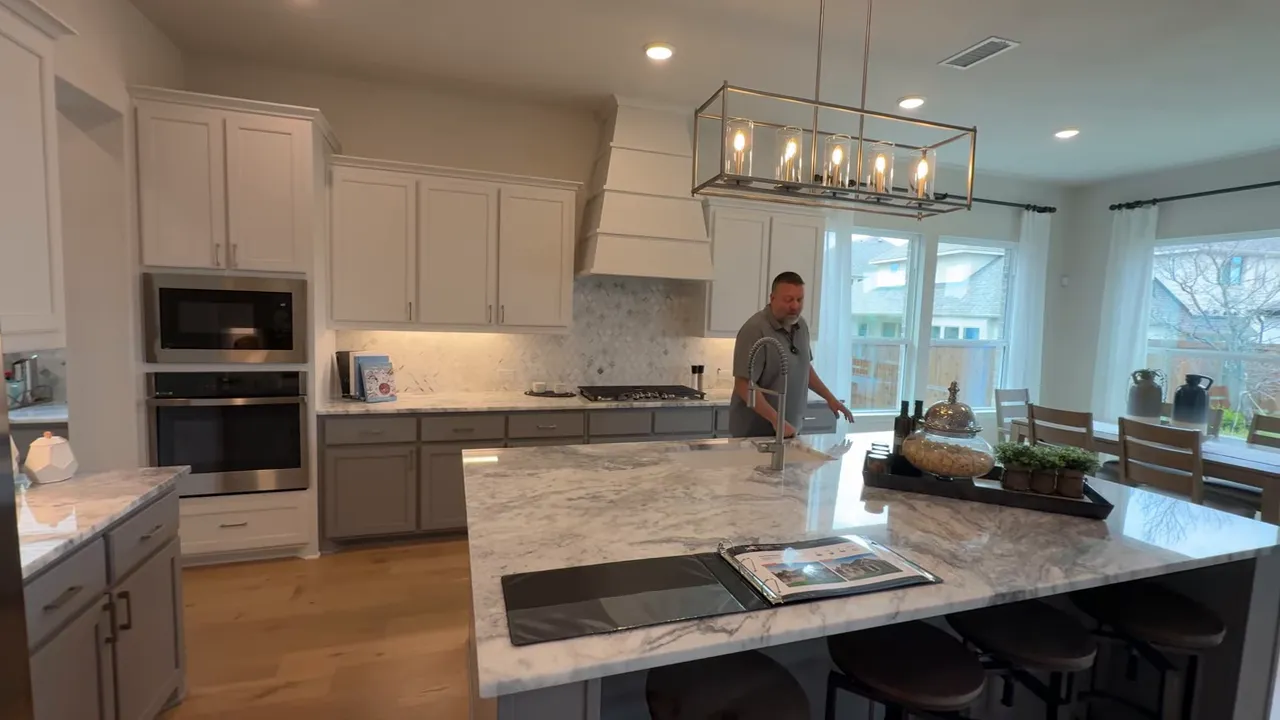 Pacesetter model kitchen and living area with large island and builder showing the space in Park Hills