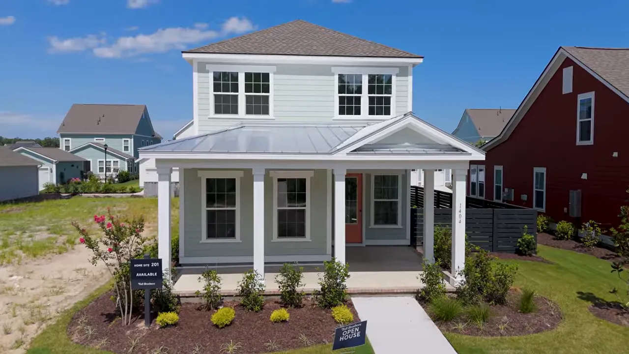 White coastal home with a large covered front porch and coral front door