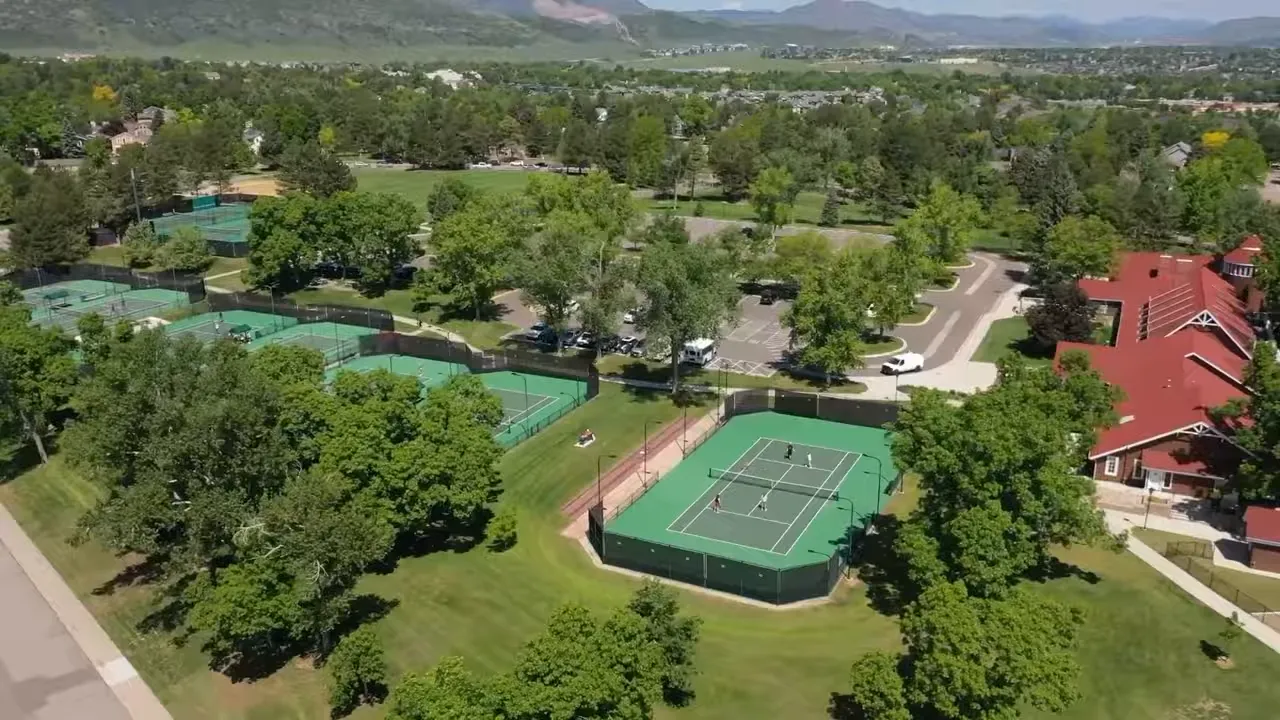 Aerial view of tennis courts and green open space with foothills in the background
