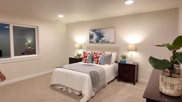 Spacious primary bedroom with bed nightstands and large window