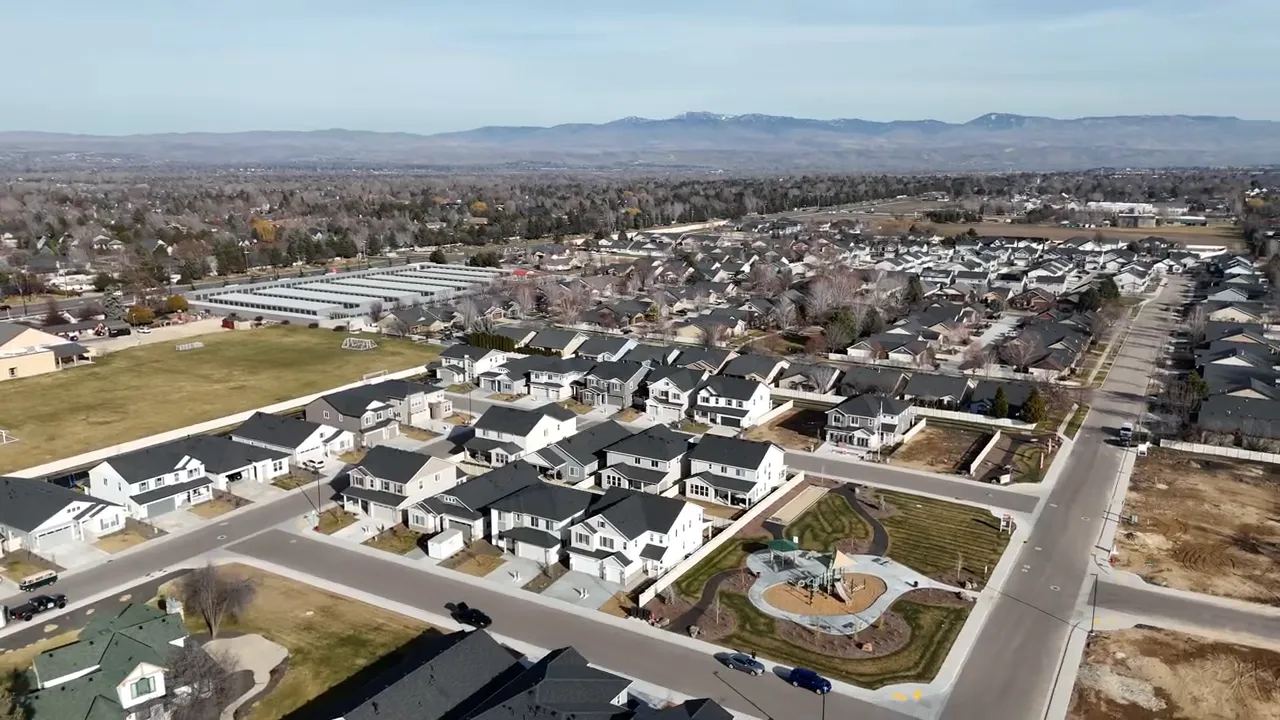 Drone aerial view of Meridian neighborhoods, local park, and mountains on the horizon