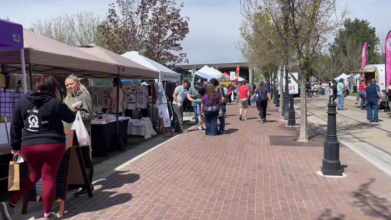 outdoor market with vendor tents people walking and browsing booths