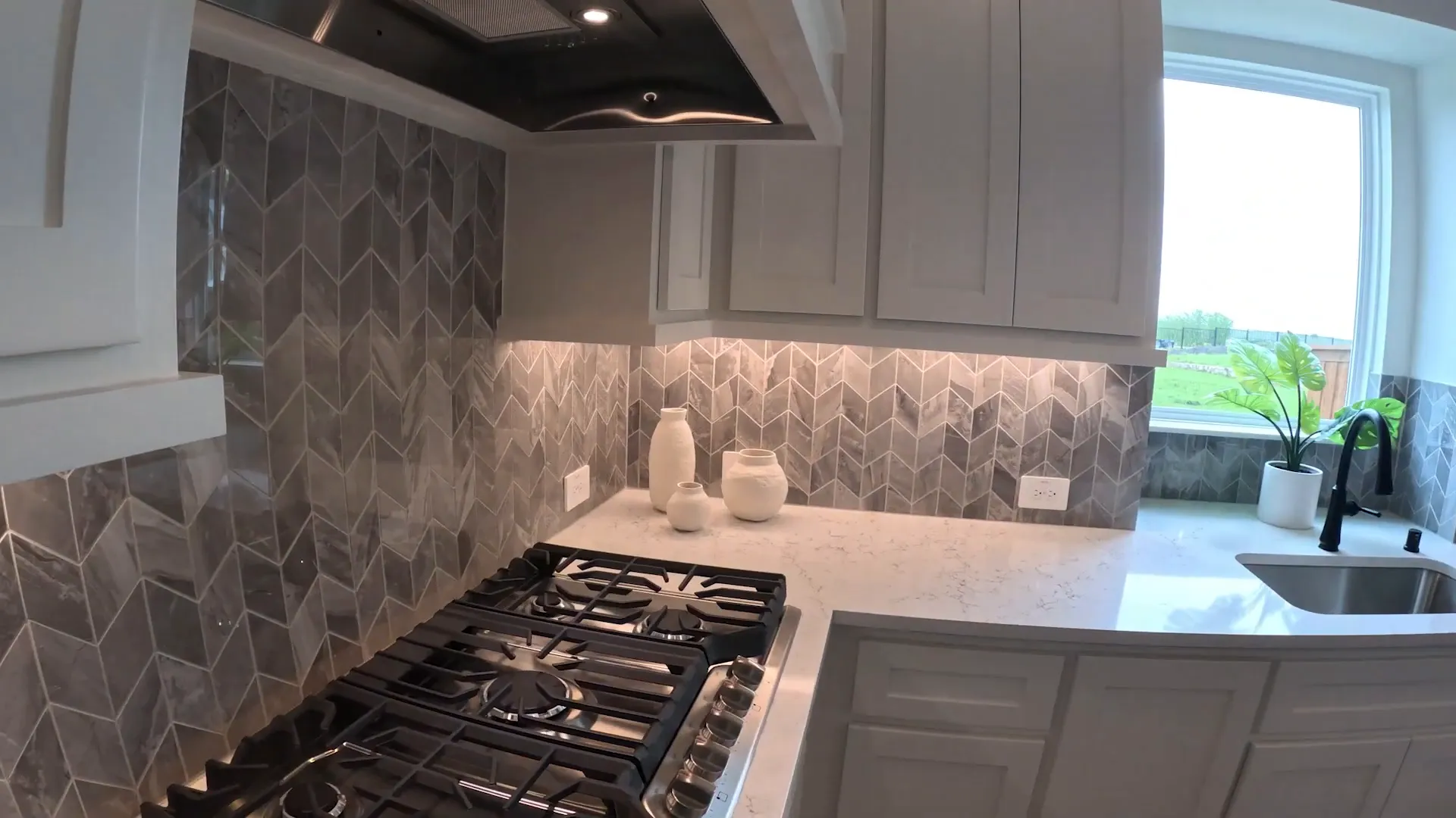 Kitchen with gas cooktop patterned backsplash and white counters