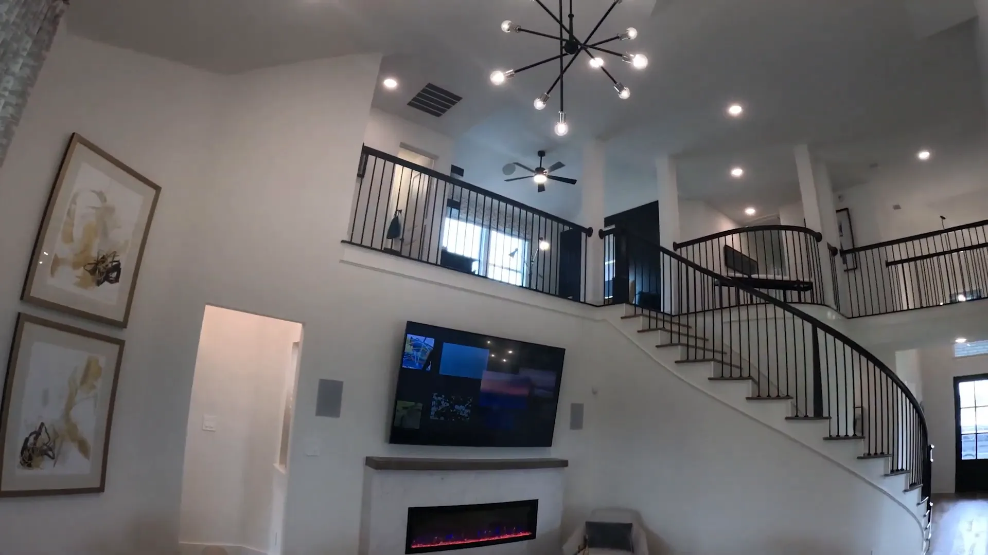 Two-story living room with fireplace curved staircase and upstairs railing