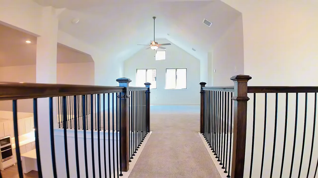 Upstairs catwalk hallway with black railings leading to a large game room