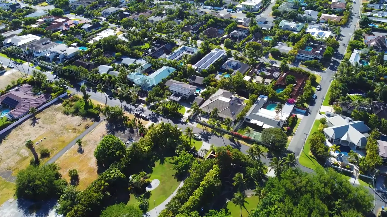 Overhead view of large homes, yards and pools in a tree-lined Kahala neighborhood