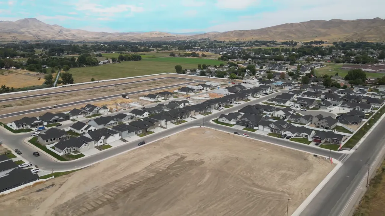 wide aerial shot of homes, empty lots and surrounding valley and hills
