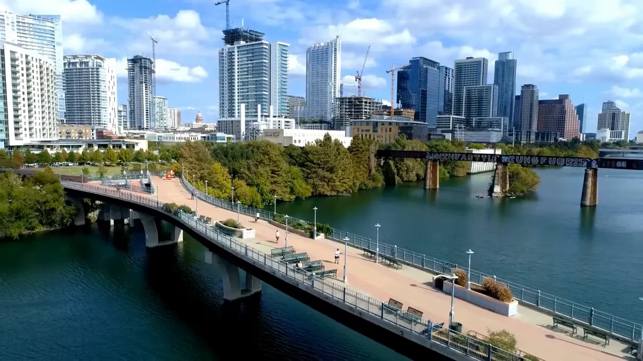 Aerial view of Lady Bird Lake with pedestrian bridge and downtown Austin skyline
