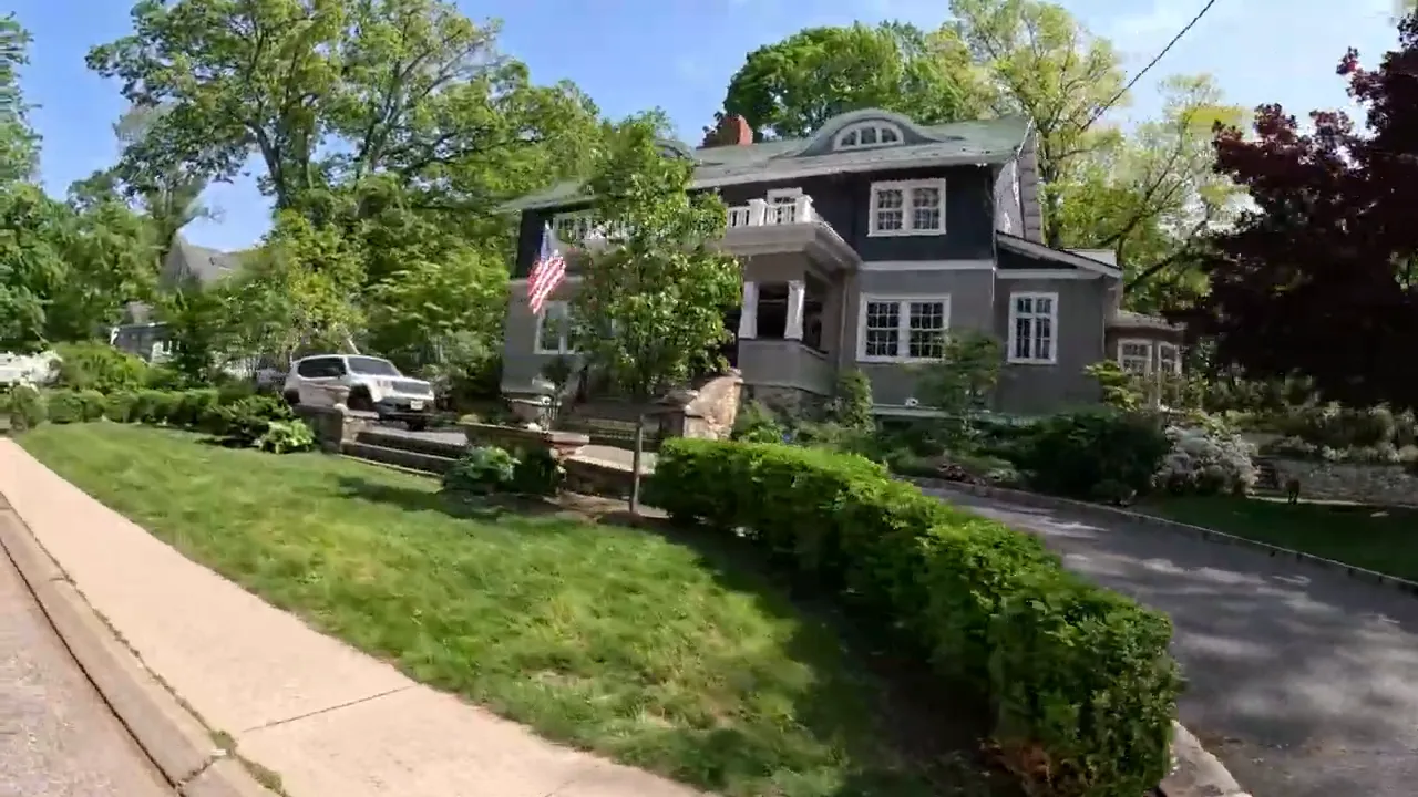 residential street with large home driveway sidewalk and landscaped front yard