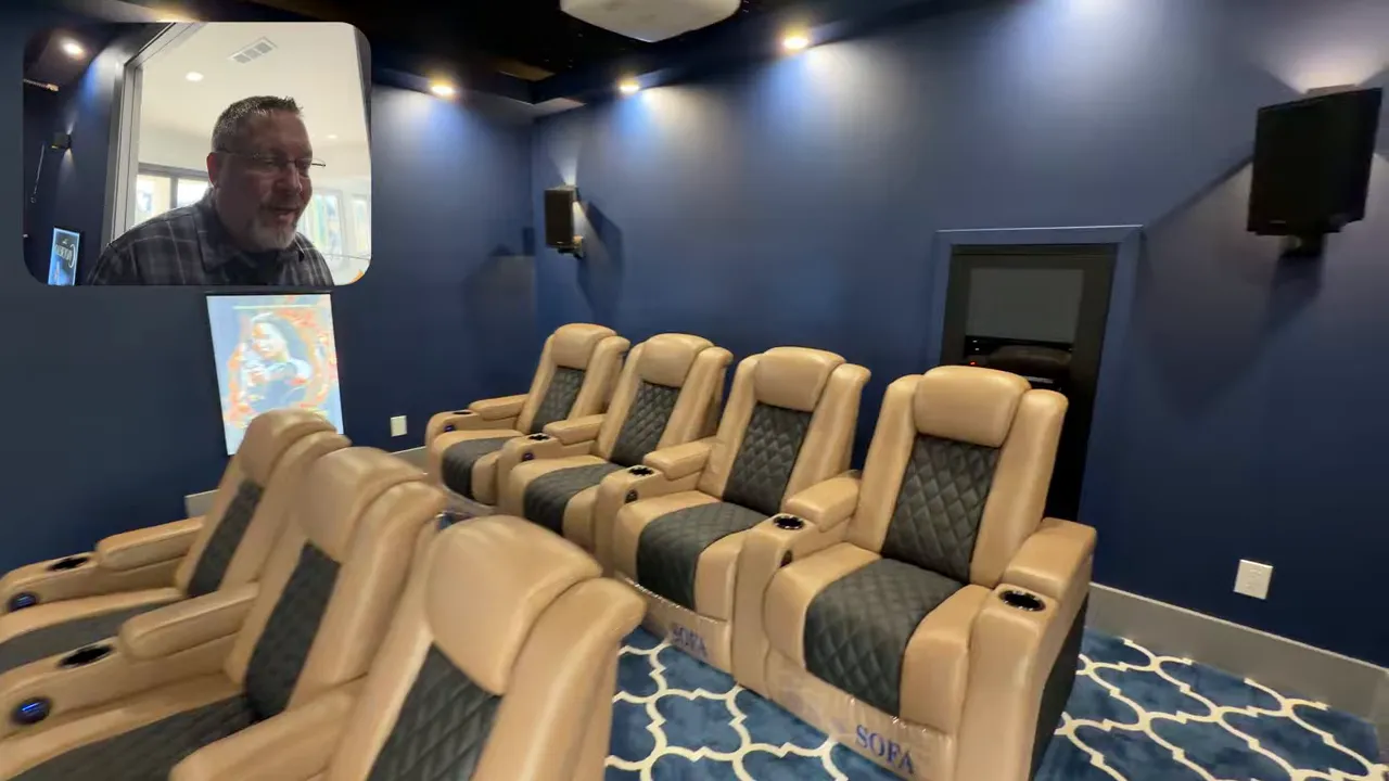 Home theater room with tan reclining stadium seats, navy blue walls and wall-mounted speakers.