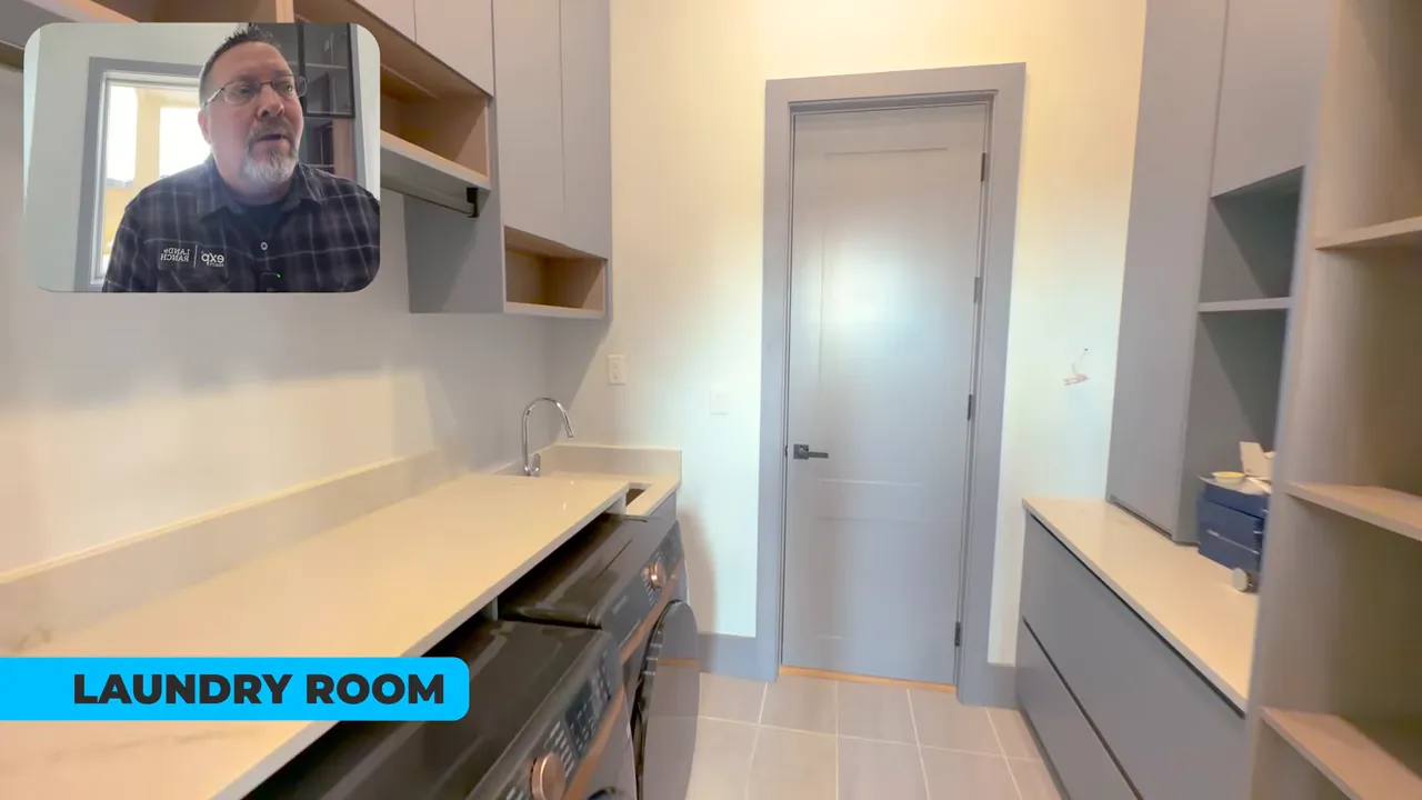 Bright laundry room with countertop, sink, front-load washer and built-in cabinets, presenter video inset