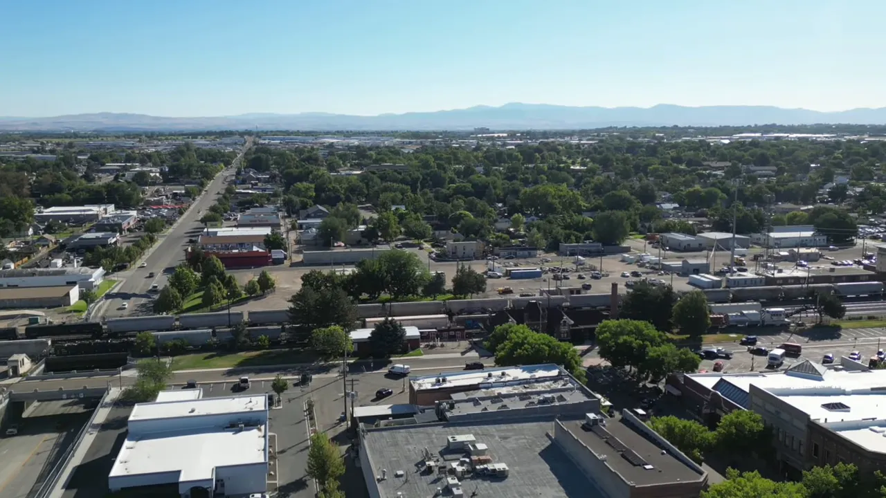 Aerial view of downtown Nampa showing streets, buildings, tree canopy and distant hills.