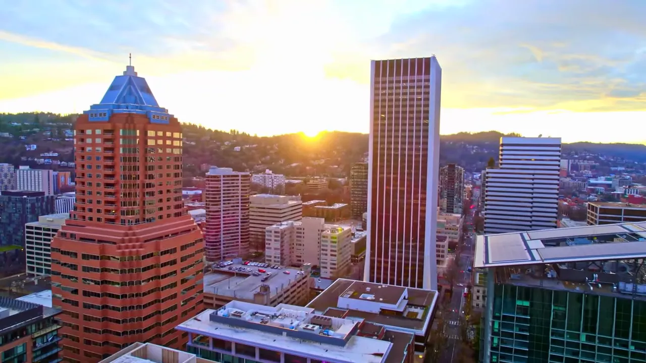 Downtown skyline at sunset with bright sun low between buildings
