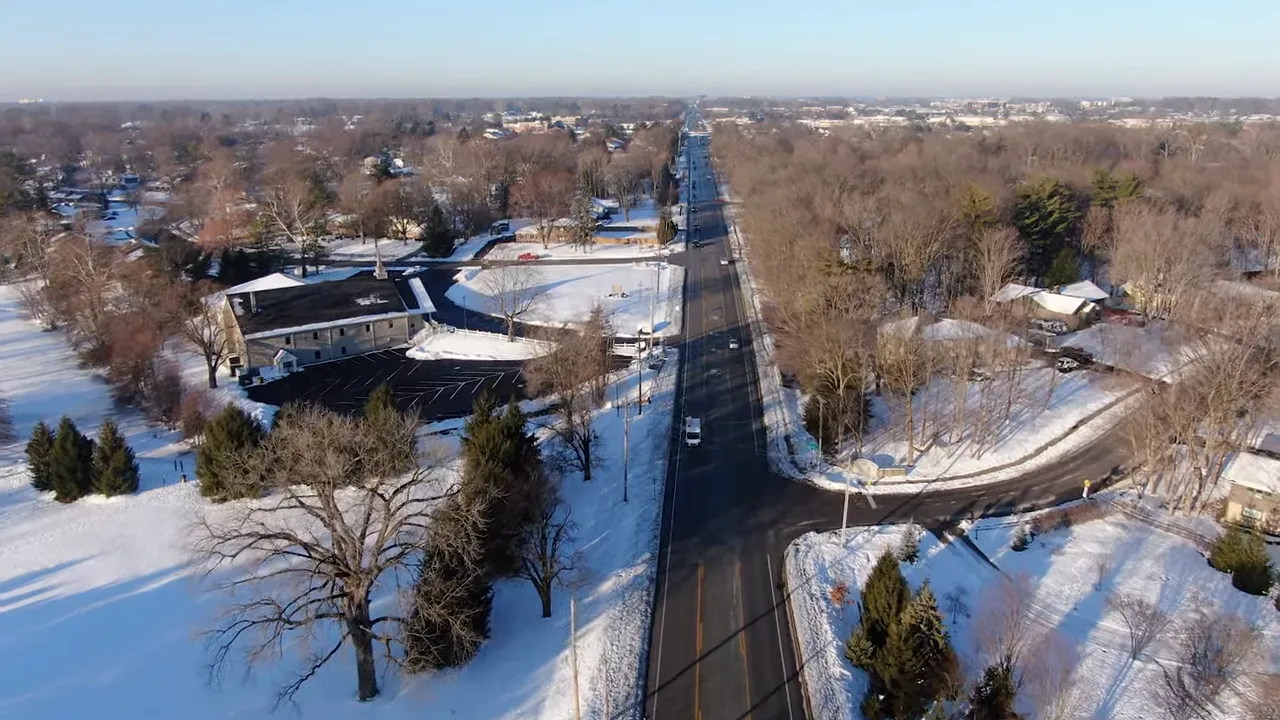 aerial view of a main road cleared of snow with snow-covered lawns on either side