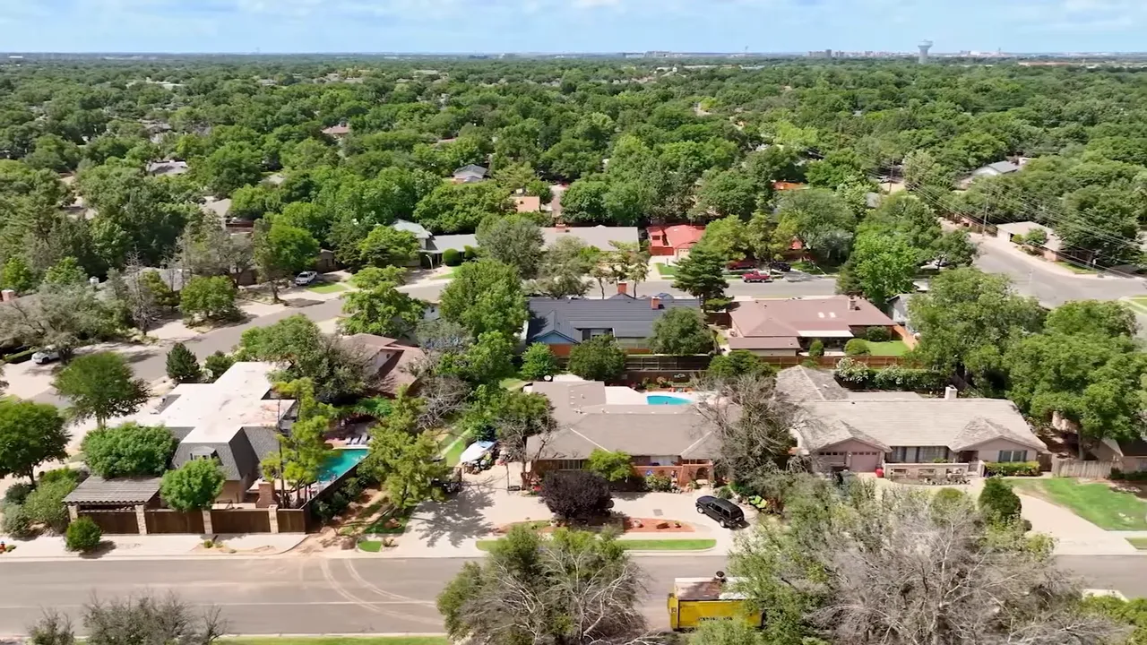 Aerial drone view of a Lubbock neighborhood with homes, pools, and tree-lined streets
