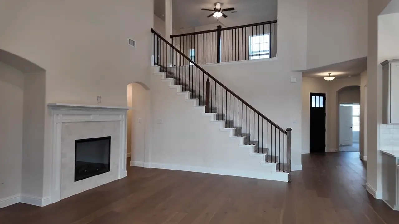 Main living area with high ceiling, staircase overlook, and fireplace in new home near Dallas Texas