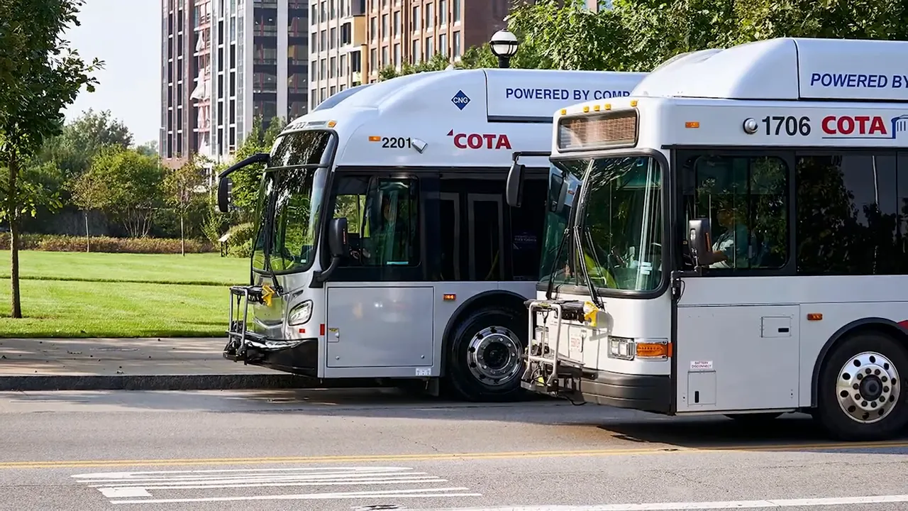Two COTA buses parked along a street near downtown buildings