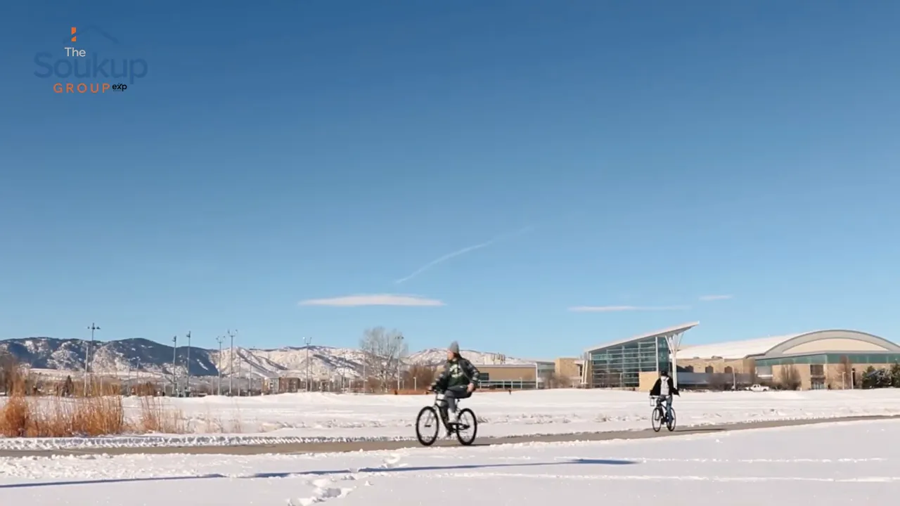 Cyclist riding on a snowy path under clear blue sky