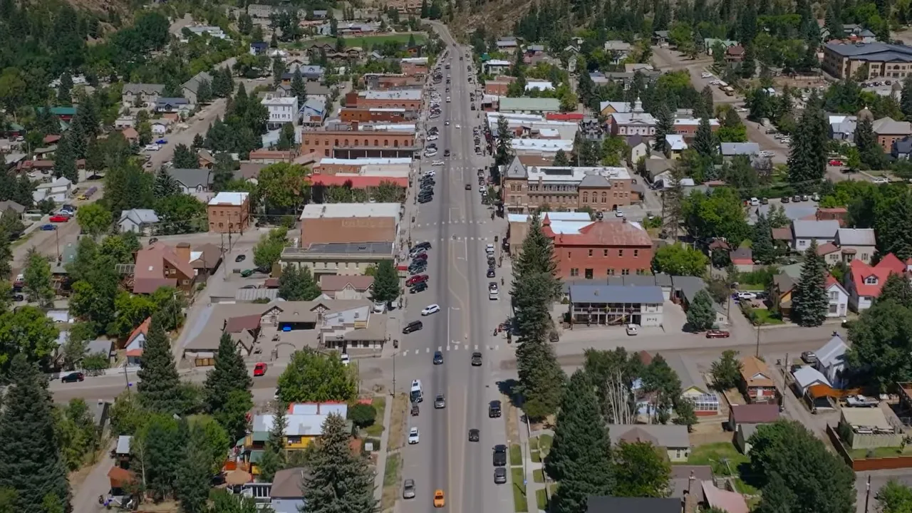 aerial view down the center of a small downtown lined with shops and homes