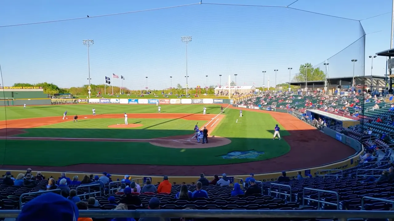 Panoramic view from near home plate showing a baseball field, players, and the surrounding stands and facilities.