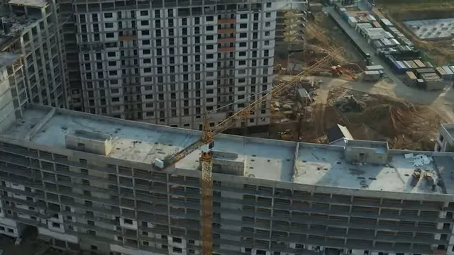 Large apartment buildings under construction with cranes and construction equipment