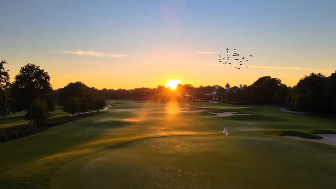 Golf course fairway at sunset with flag and golfers in the distance
