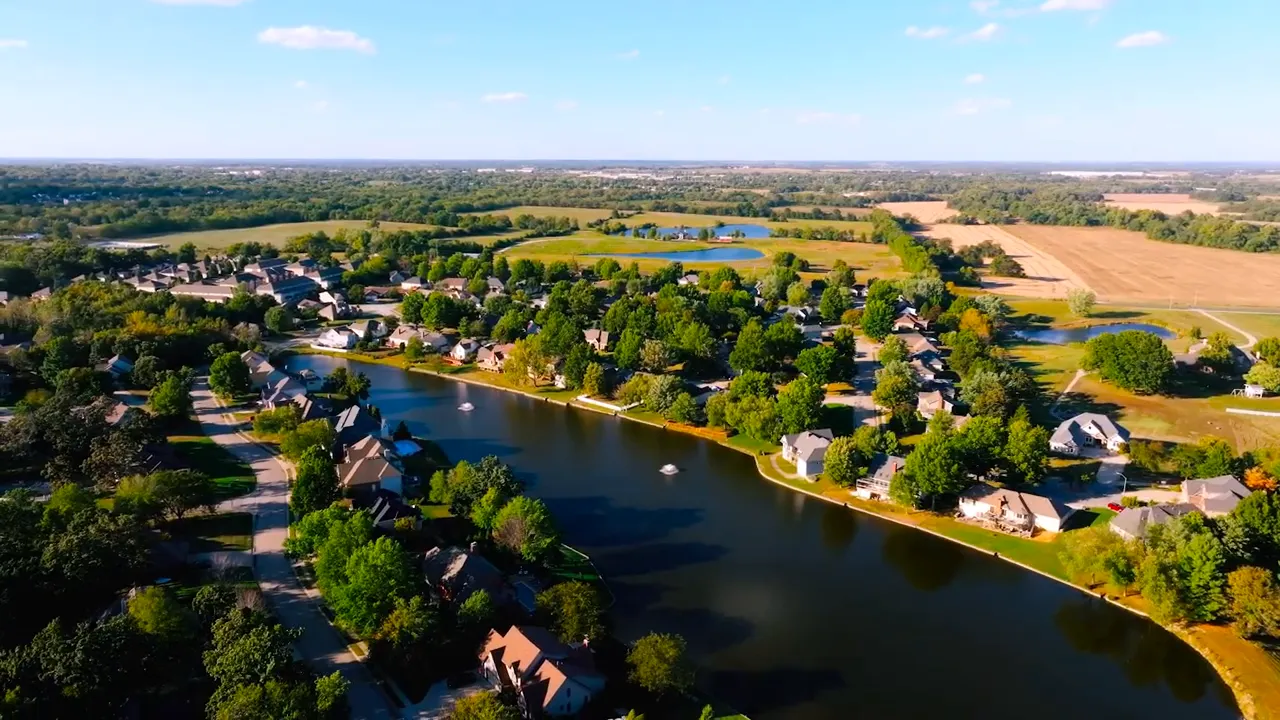 Drone aerial view of Lake Ridge lake with homes and trees in Warrensburg MO
