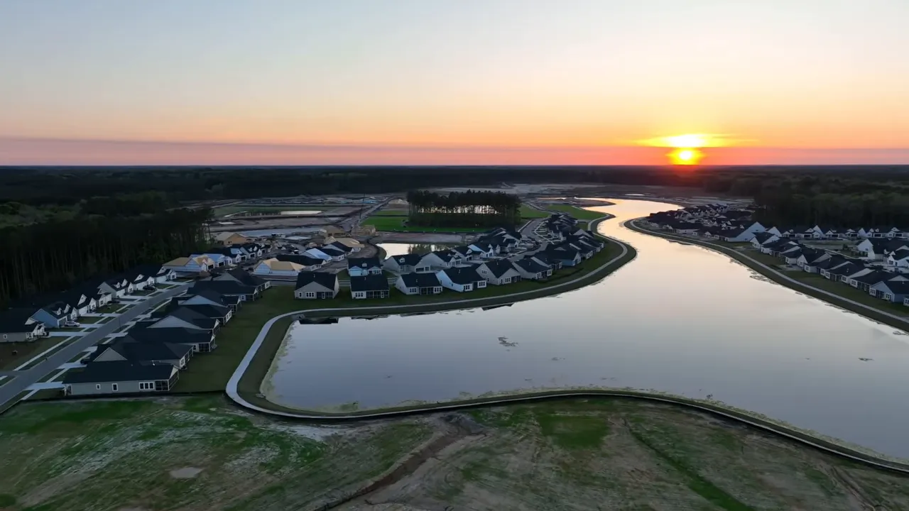 Aerial view of Summers Corner neighborhood homes and a curving lake at sunset in Summerville, South Carolina