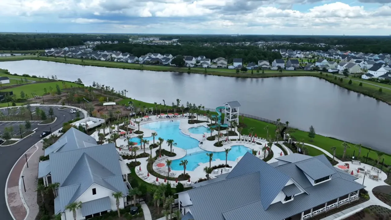 Aerial view of neighborhood amenities with a large pool area beside a lake