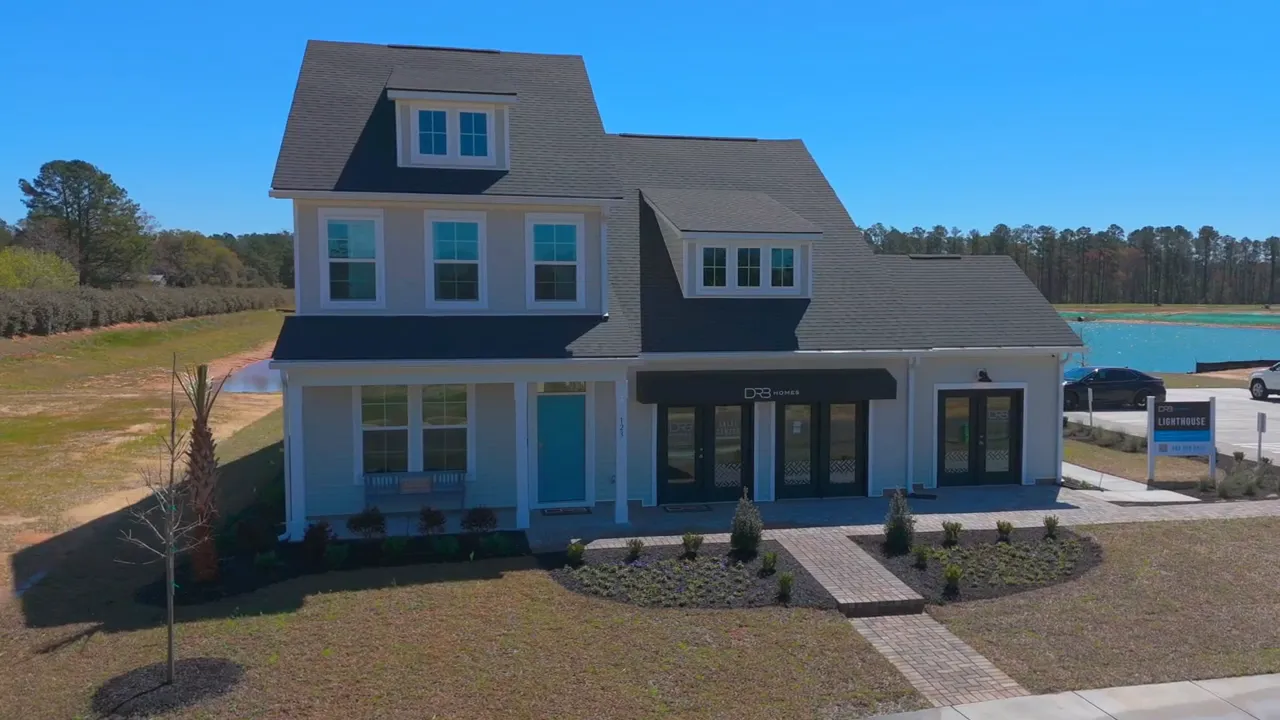 Front exterior of a large new construction home with driveway and surrounding lots