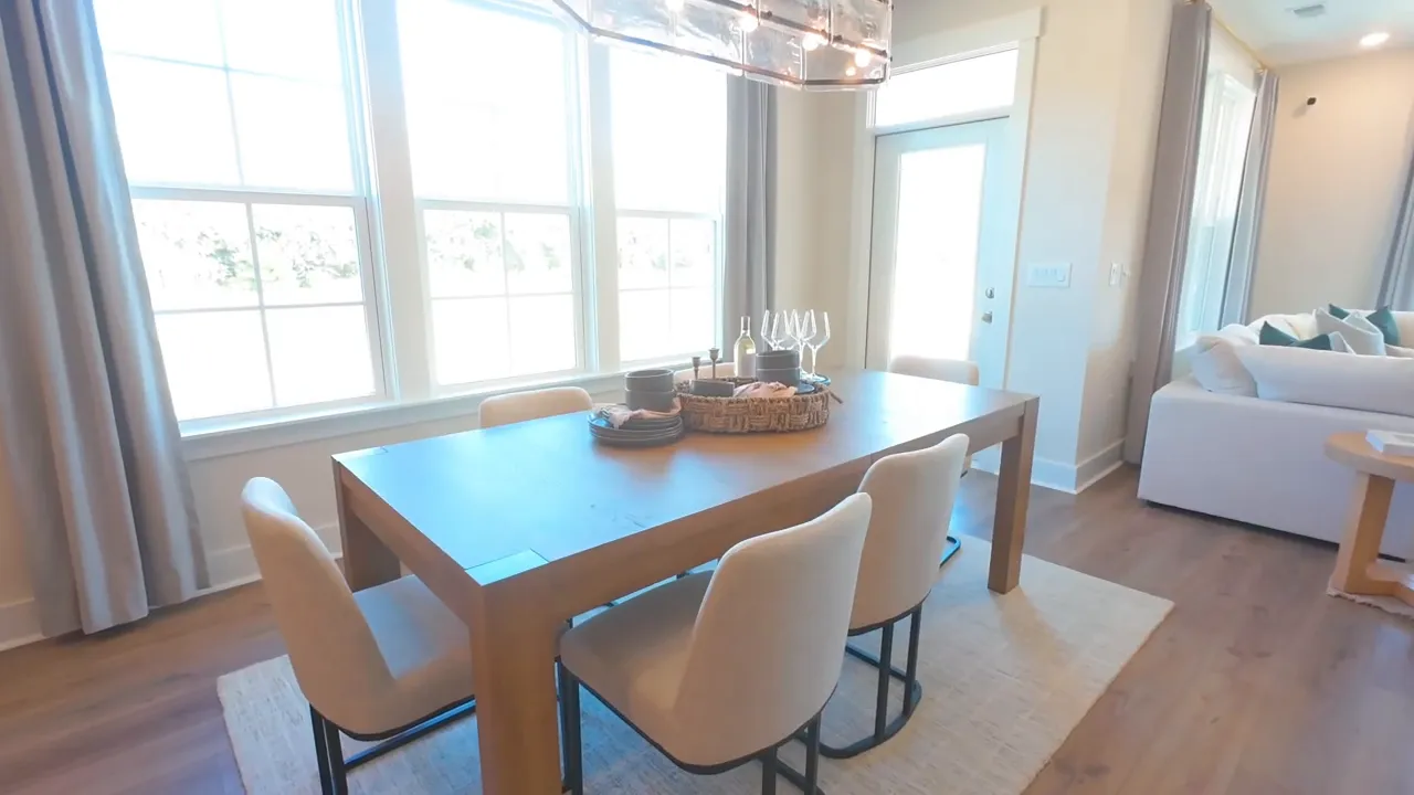 Dining area with large table chandelier and tall windows beside glass door