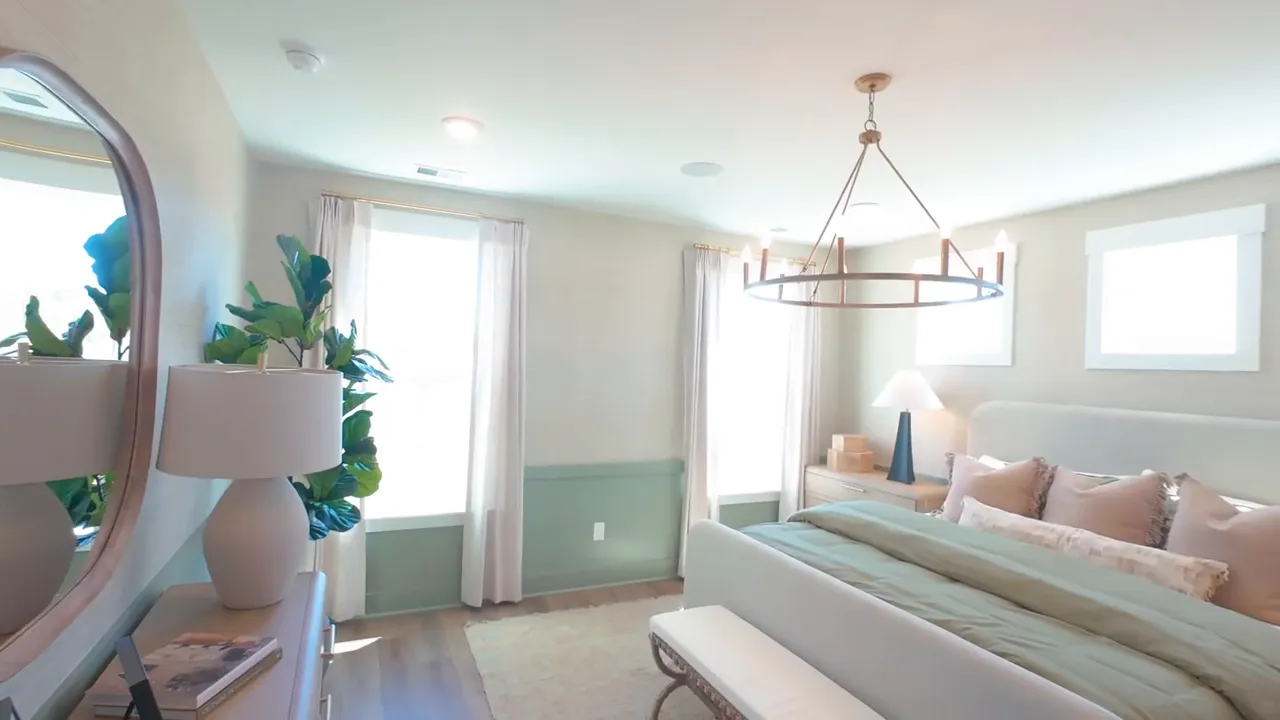 Primary bedroom with large bed chandelier bench and high windows
