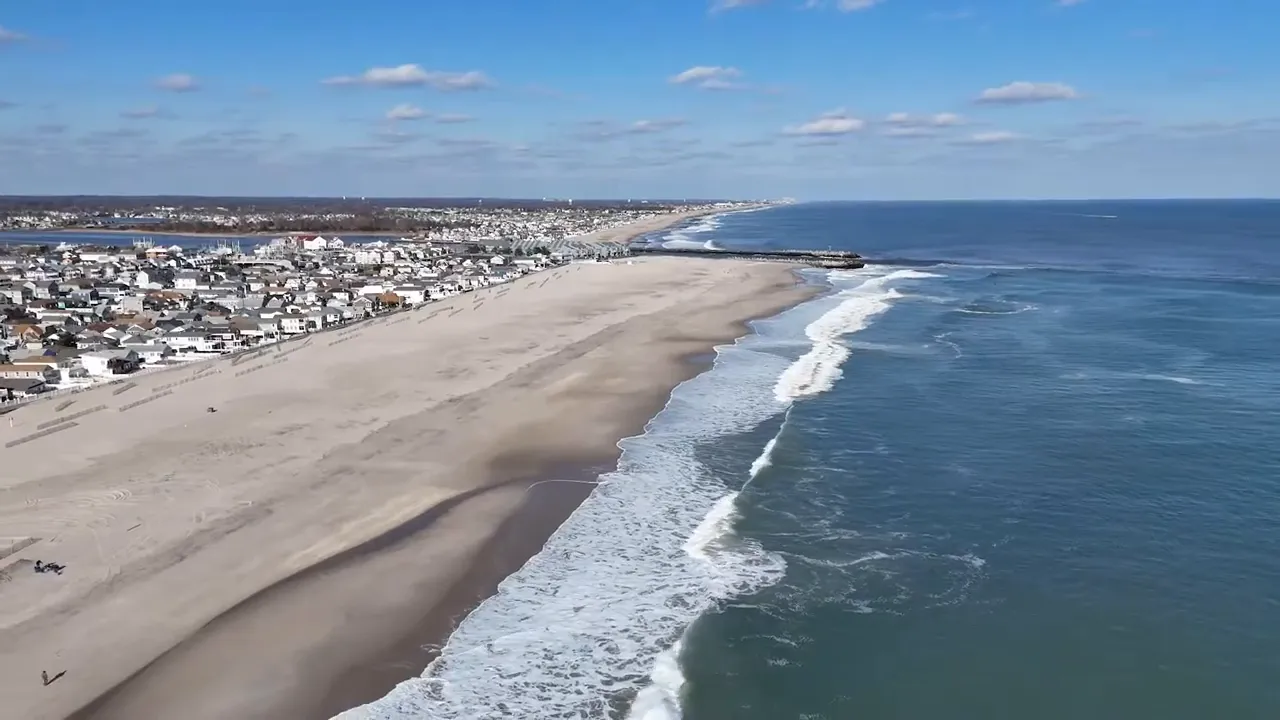Aerial coastline view of the Jersey Shore with wide sandy beach, waves, and beachfront houses