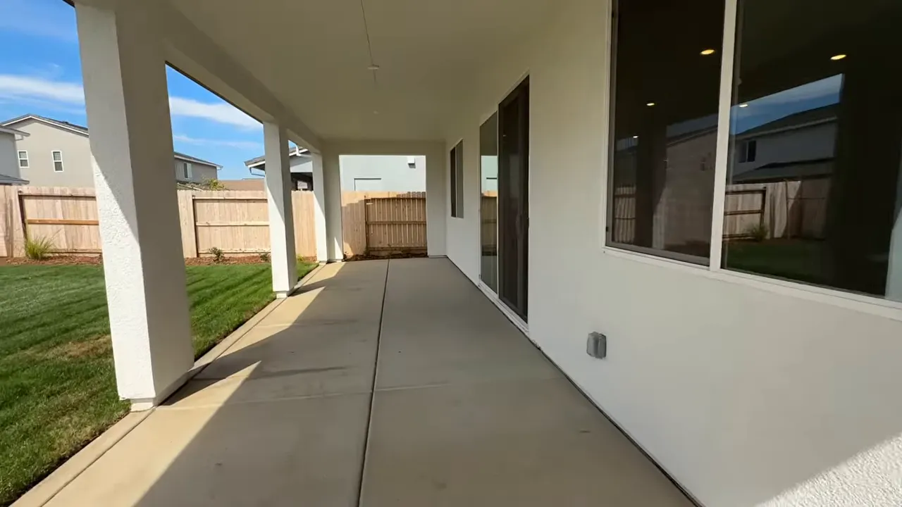 Outdoor covered patio walkway and concrete area beside a modern home