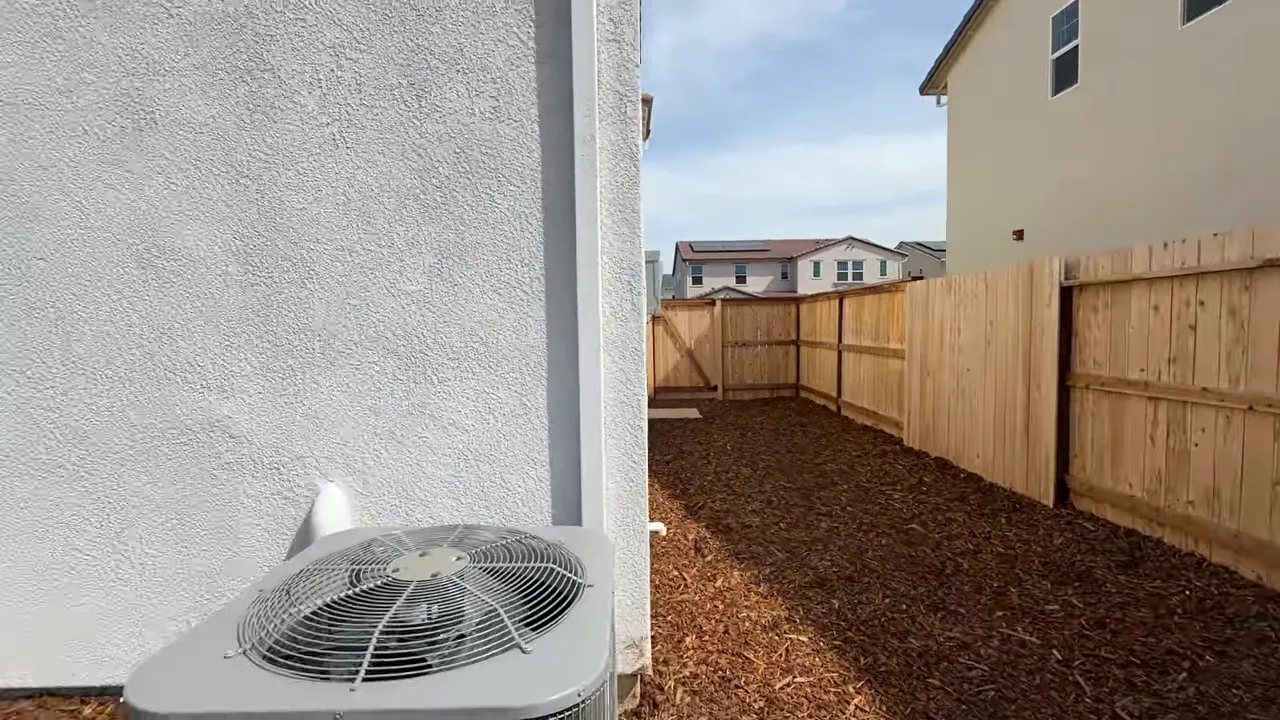 Practical side yard with mulch landscaping and wooden fence near HVAC unit at Arbor Ranch Elk Grove