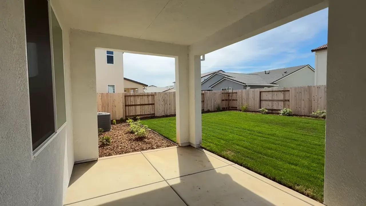 Back patio and backyard lawn area with privacy fence in Arbor Ranch quick move-in home in Elk Grove CA