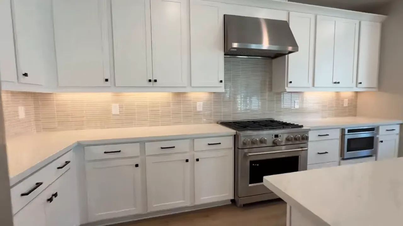 Upgraded kitchen with white cabinets, tiled backsplash, gas range, and stainless appliances in Arbor Ranch Elk Grove home